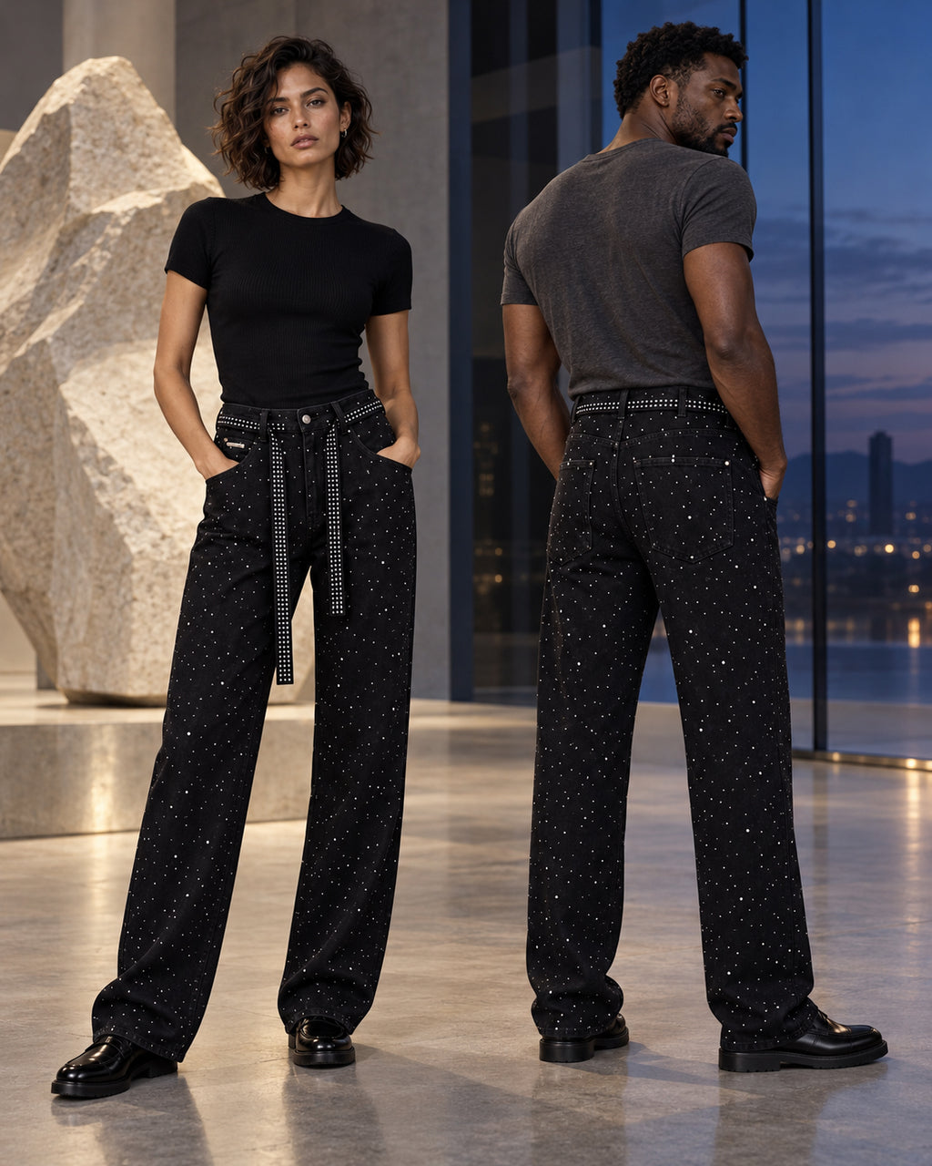 Femme et homme portant le jean à strass noir DIFFERENT avec t-shirts, devant une baie vitrée de nuit – DIFFERENT Paris