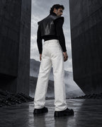 Homme de dos portant le jean à strass blanc DIFFERENT avec gilet en cuir noir, face à un paysage brumeux – DIFFERENT Paris