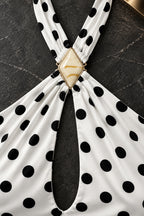 Détail du bijou doré au centre du décolleté de la robe à pois