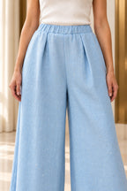 Gros plan sur la taille élastique et les pinces du pantalon bleu ciel