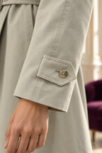 Détail de la patte boutonnée au poignet du trench beige