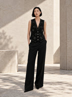 Femme portant le gilet noir structuré à clous argentés et diamants DIFFERENT avec pantalon large noir, dans une cour ensoleillée – DIFFERENT Paris
