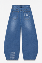 Jean femme DIFFERENT bleu stone vu de dos, coupe ballon taille haute avec poches arrière, logo graphique et motif ton sur ton.
