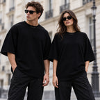 Homme et femme portant le t-shirt oversize premium noir DIFFERENT avec lunettes de soleil, dans une rue parisienne – DIFFERENT Paris