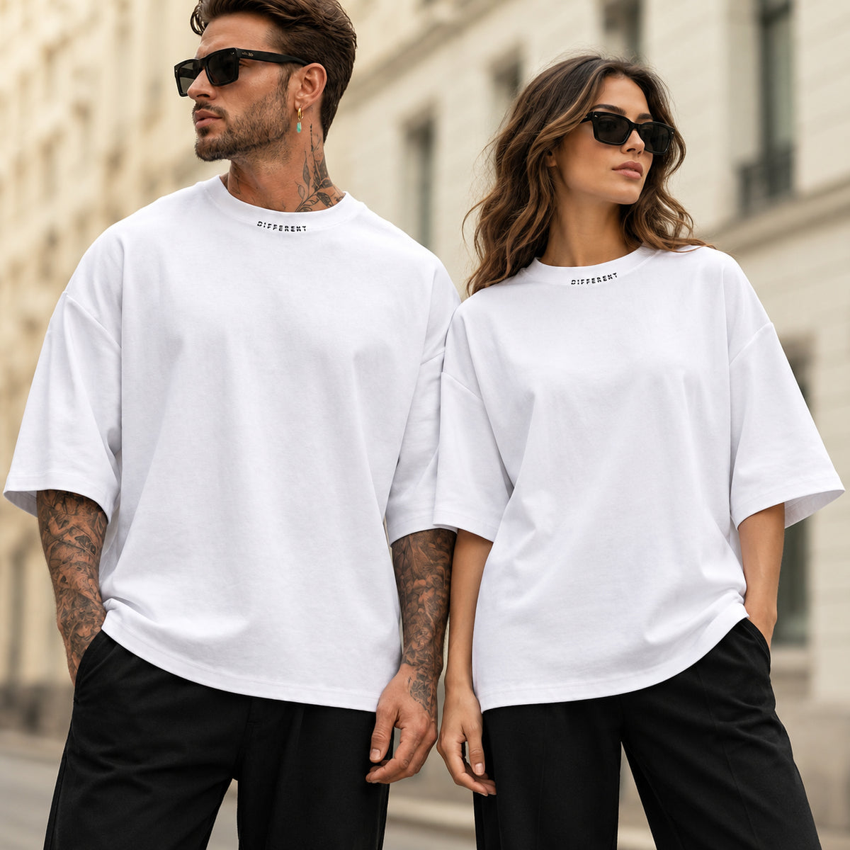 Homme et femme portant le t-shirt oversize premium blanc DIFFERENT avec lunettes de soleil, dans une rue parisienne – DIFFERENT Paris