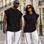 Homme et femme portant le t-shirt sans manches oversize noir DIFFERENT en coton épais 260 g avec pantalon blanc à bandes, dans une rue de Paris – DIFFERENT Paris