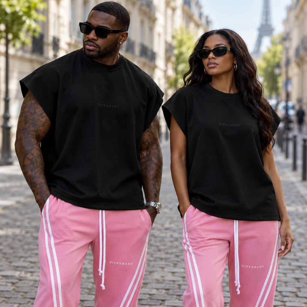 Homme et femme portant le débardeur oversize noir effet spandex brodé DIFFERENT avec jogging rose à bandes, près de la tour Eiffel – DIFFERENT Paris