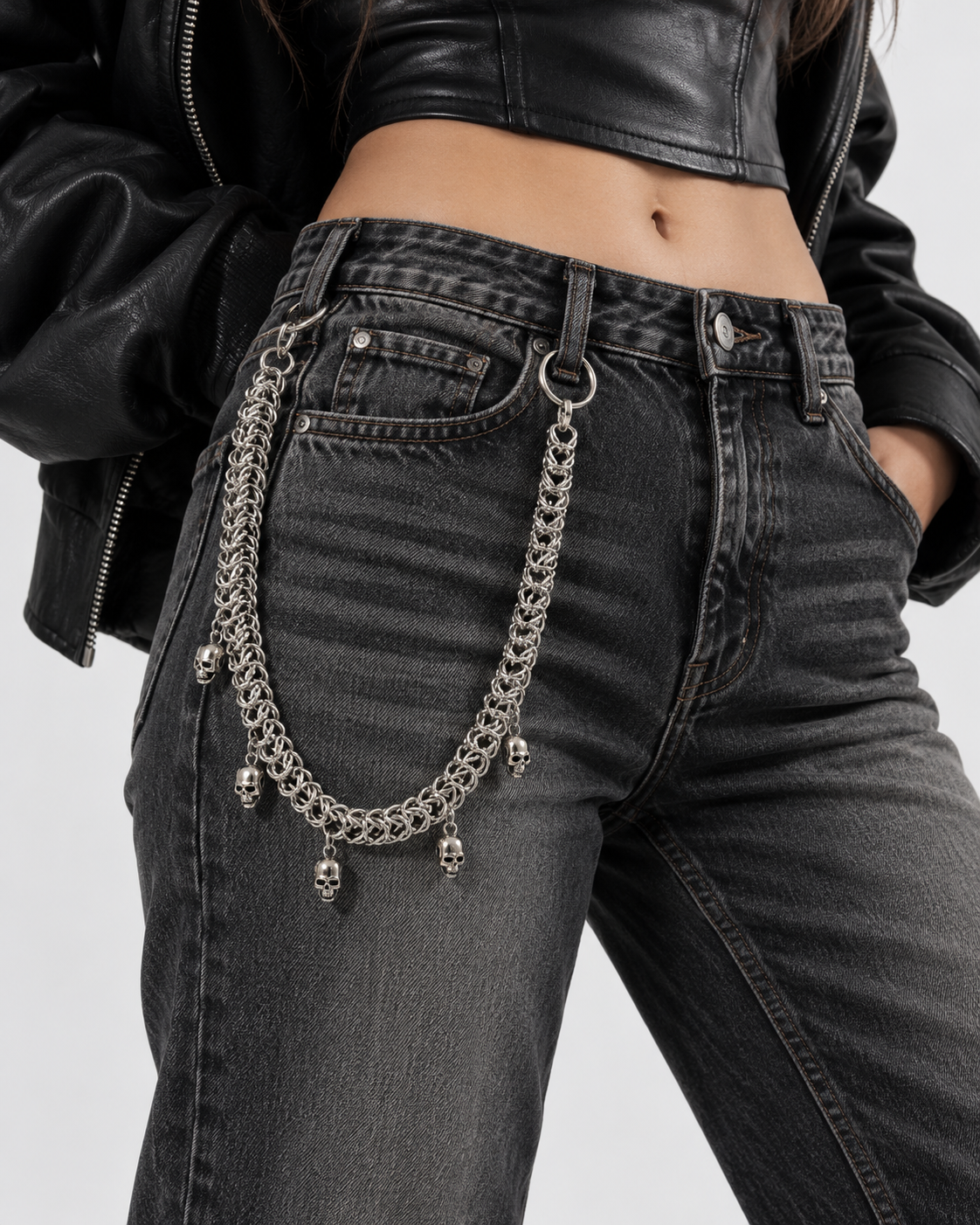 Chaîne de pantalon REAPER en acier inoxydable, maille tressée et pendentifs têtes de mort, portée sur un jean noir – DIFFERENT Paris