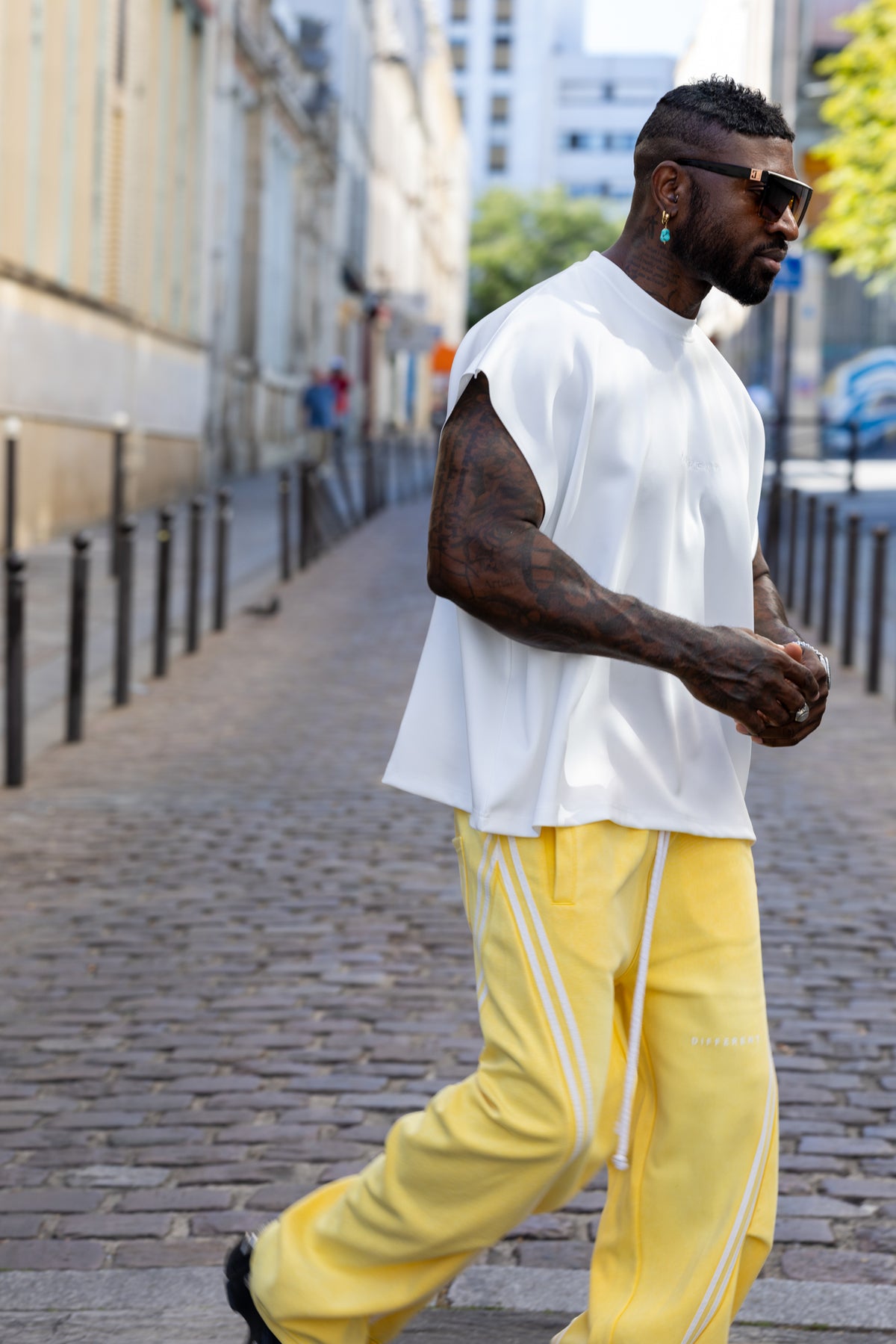 T-shirt blanc oversize unisexe DIFFERENT porté en look streetwear avec pantalon large jaune