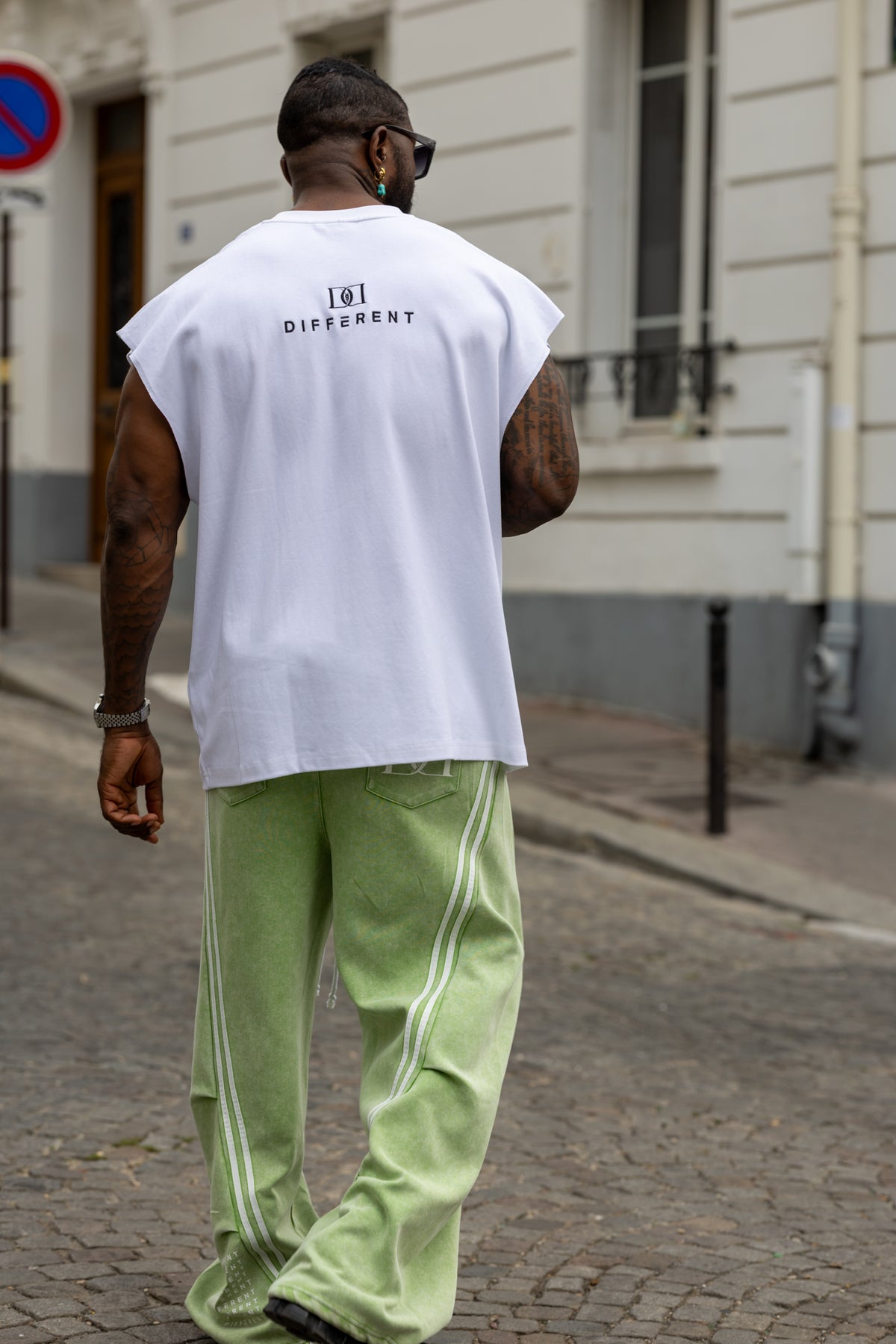 T-shirt streetwear DIFFERENT blanc et vert porté de dos avec pantalon oversize à bandes latérales