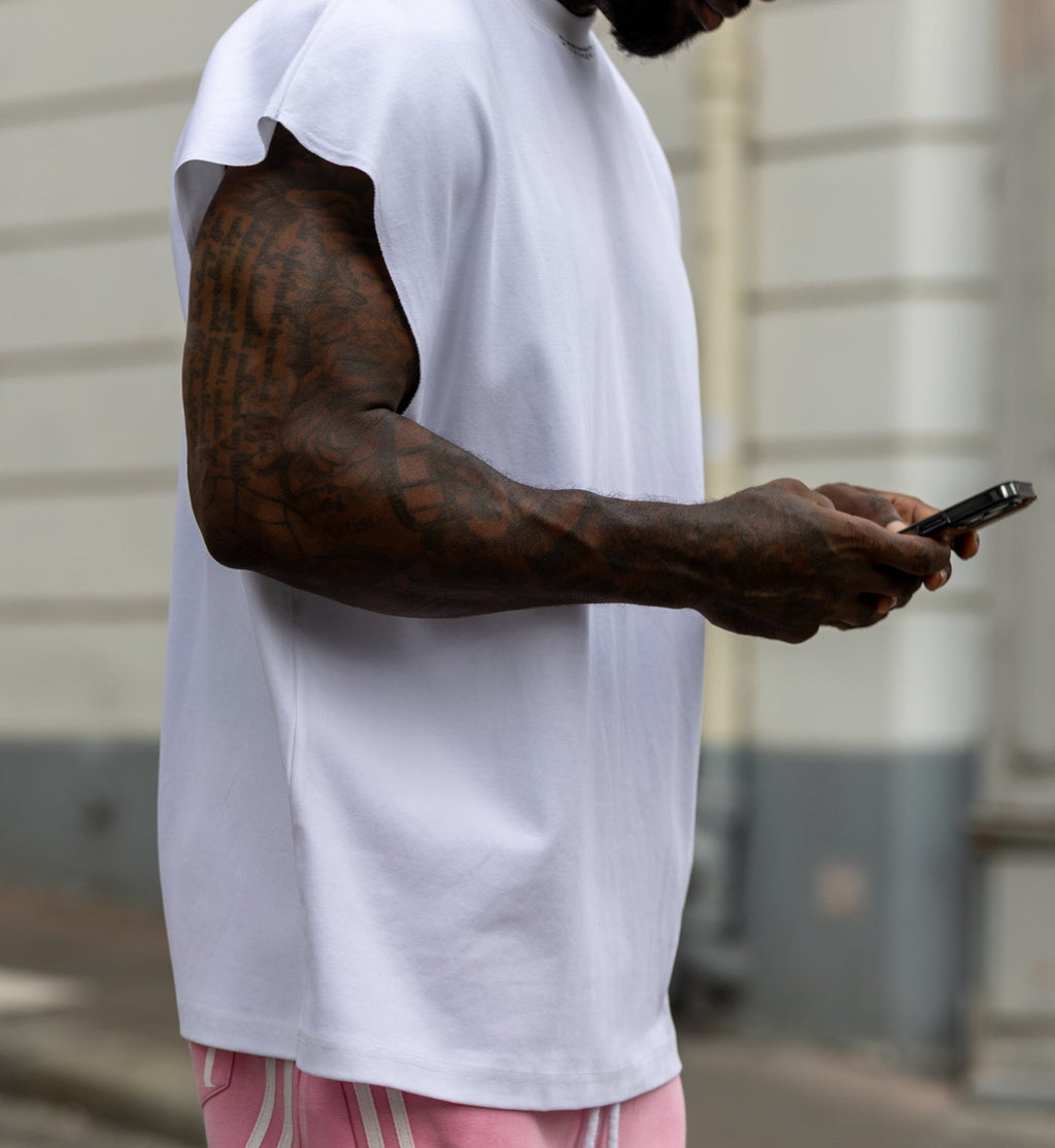 T-shirt blanc oversize sans manches DIFFERENT avec pantalon rose à bandes blanches – vue de profil