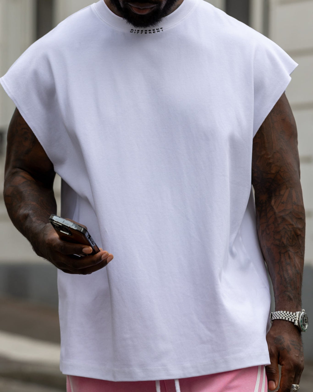 T-shirt blanc sans manches oversize DIFFERENT porté avec pantalon rose – détail du look