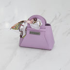 Mini sac DIFFERENT lilas avec foulard imprimé pastel, poignée arrondie et plaque logo métallique.