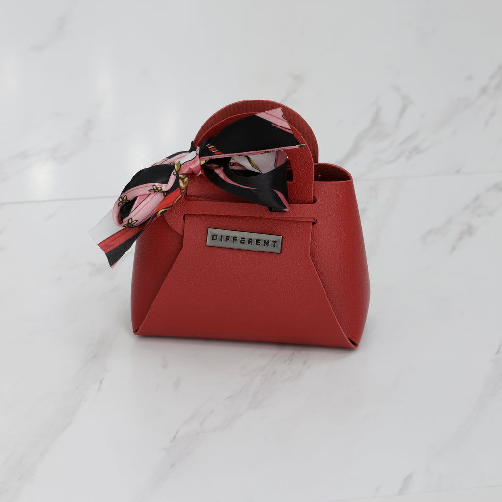 Mini sac DIFFERENT rouge avec foulard imprimé noir, rose et blanc, poignée rigide et finition effet cuir.