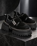 Paire de chaussures à plateforme femme noires DIFFERENT avec chaînes argentées, posée sur un socle en pierre noire – DIFFERENT Paris