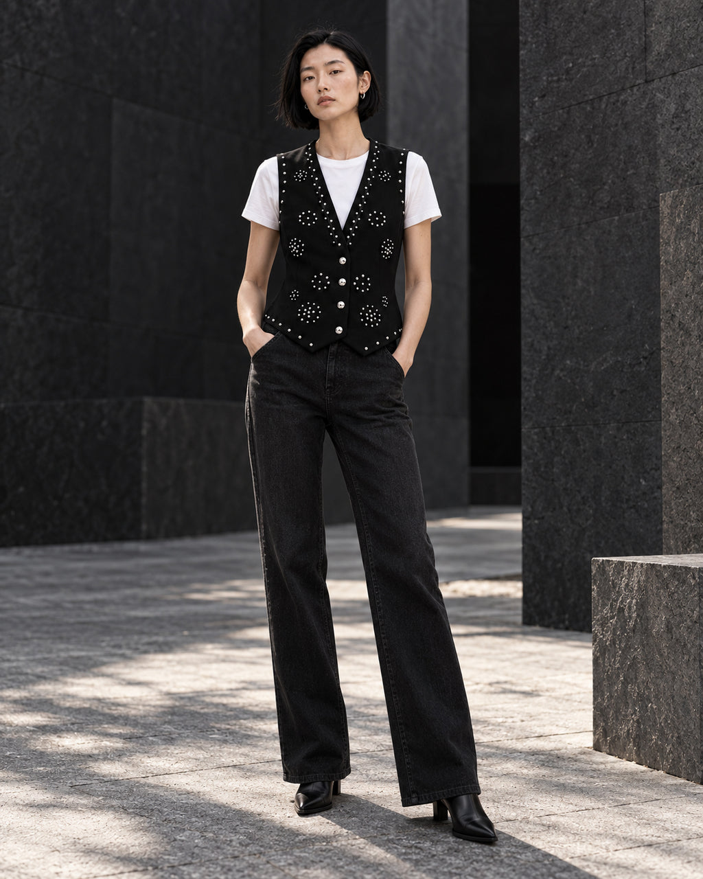 Femme portant le gilet noir à clous argentés et diamants DIFFERENT avec t-shirt blanc et pantalon noir droit – DIFFERENT Paris