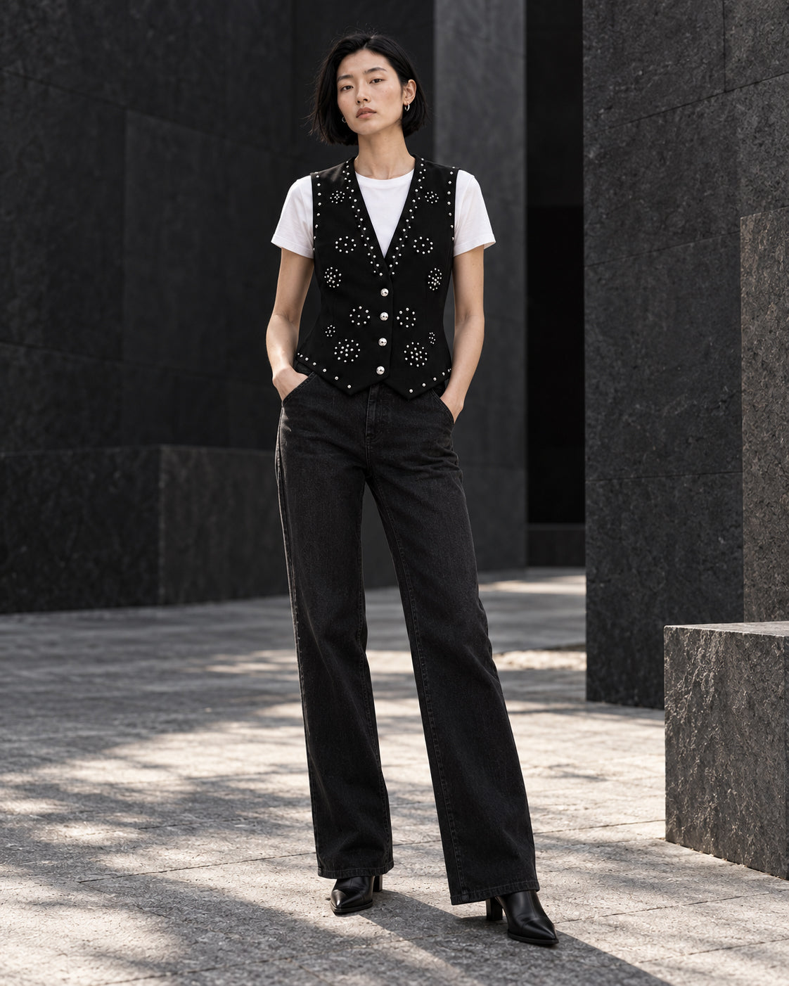 Femme portant le gilet noir à clous argentés et diamants DIFFERENT avec t-shirt blanc et pantalon noir droit – DIFFERENT Paris