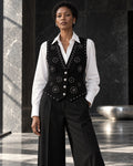 Femme portant le gilet noir structuré à clous argentés et diamants DIFFERENT avec chemise blanche et pantalon noir large – DIFFERENT Paris