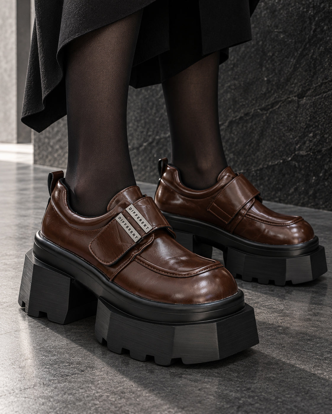 Chaussures femme à plateforme noire DIFFERENT en similicuir marron brillant, portées avec collants noirs – DIFFERENT Paris