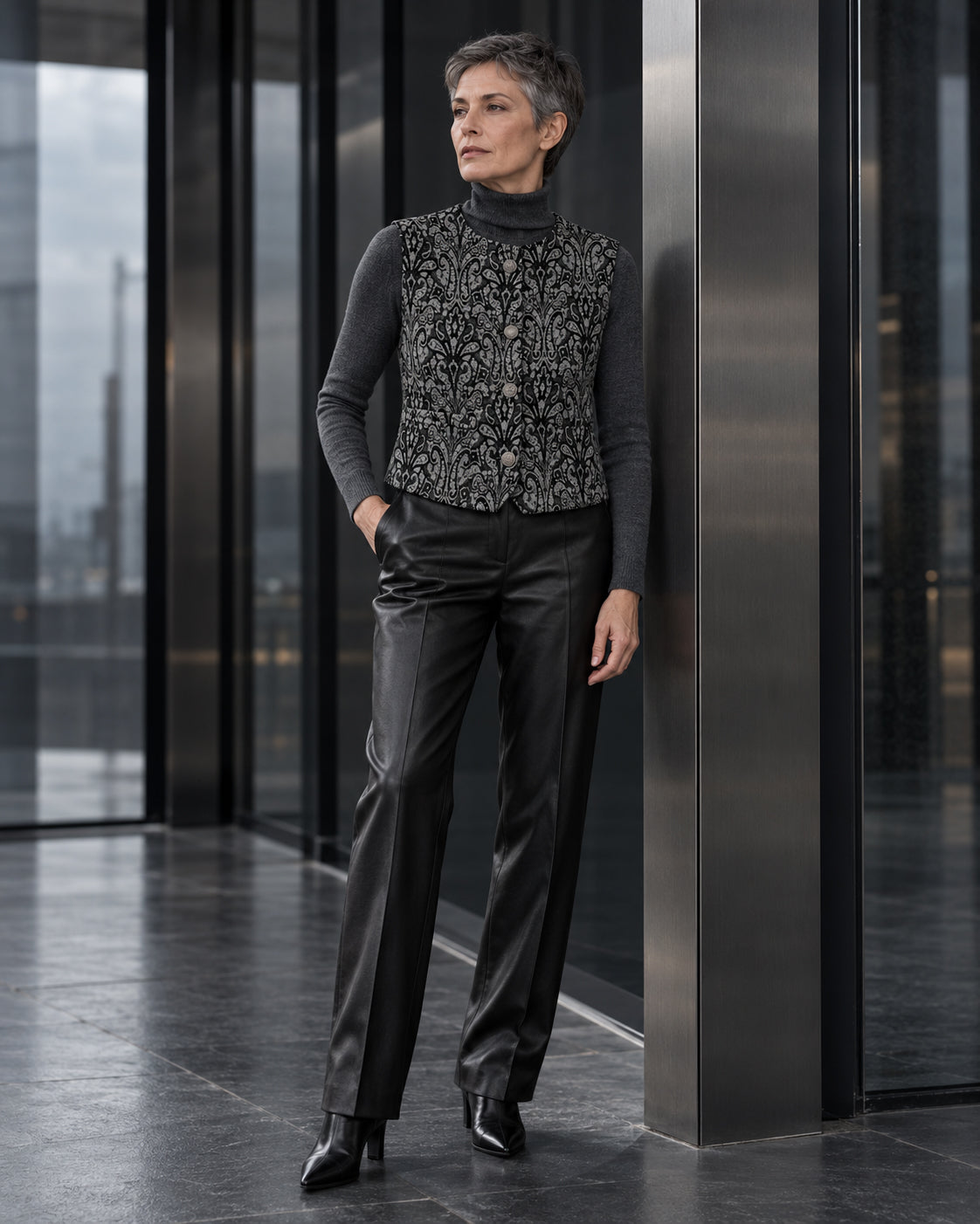Femme portant le gilet court à motif baroque noir et gris DIFFERENT avec col roulé gris et pantalon gris – DIFFERENT Paris