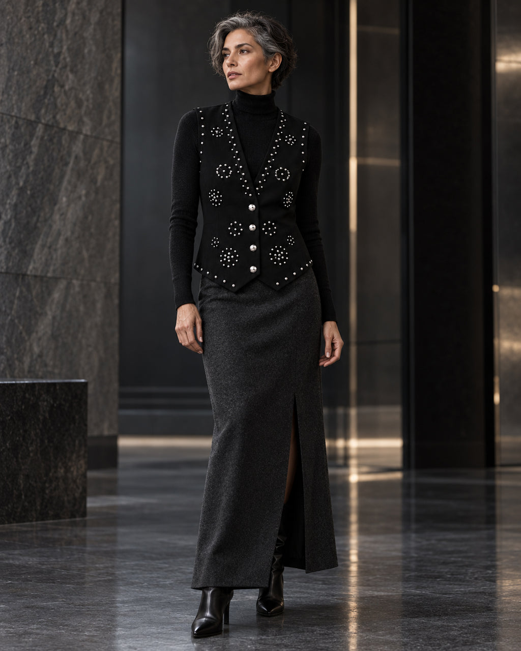 Femme portant le gilet noir à clous argentés et diamants DIFFERENT avec col roulé noir et jupe longue noire – DIFFERENT Paris