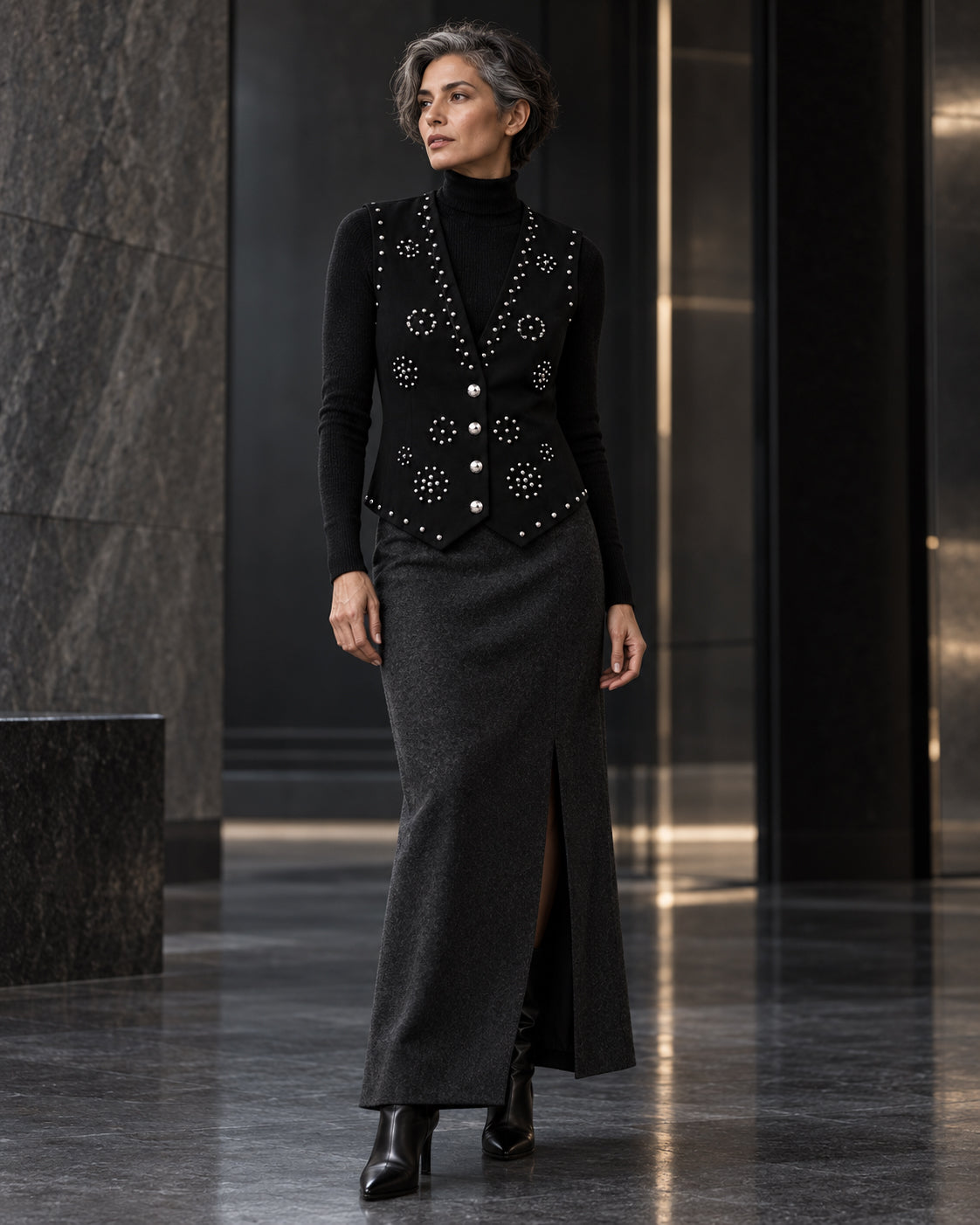 Femme portant le gilet noir à clous argentés et diamants DIFFERENT avec col roulé noir et jupe longue noire – DIFFERENT Paris