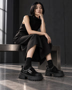 Femme assise en robe noire portant les chaussures à plateforme DIFFERENT avec chaussettes noires – DIFFERENT Paris