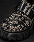 Gros plan sur le motif baroque noir et écru et la bride à plaques argentées DIFFERENT de la chaussure à plateforme – DIFFERENT Paris