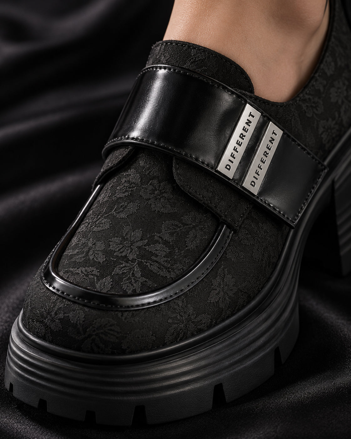 Gros plan sur le motif floral ton sur ton et la bride vernie à plaques argentées DIFFERENT de la chaussure à plateforme noire – DIFFERENT Paris