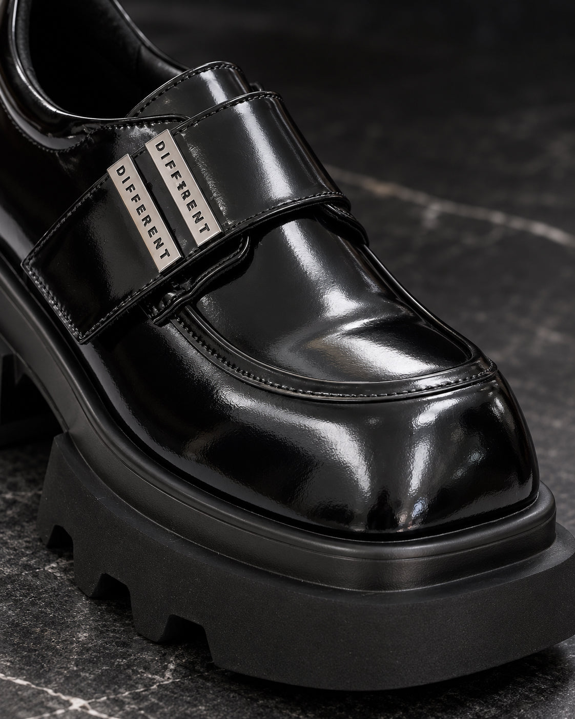 Gros plan sur la bride et les plaques argentées DIFFERENT de la chaussure plateforme femme noir brillant – DIFFERENT Paris