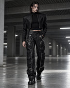 Homme portant le pantalon cargo noir en simili cuir à chaînes DIFFERENT avec veste courte noire, dans un parking – DIFFERENT Paris