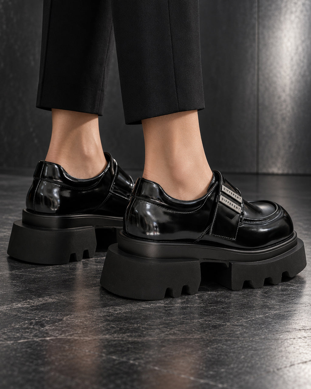 Chaussures plateforme noir brillant DIFFERENT portées avec pantalon noir, vue de trois quarts – DIFFERENT Paris