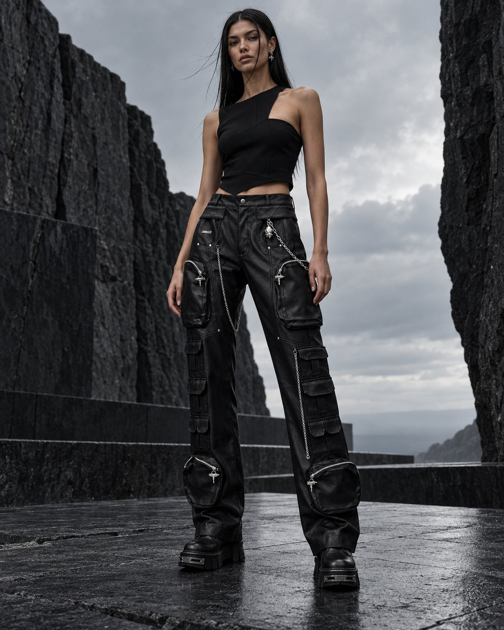 Femme portant le pantalon cargo noir en simili cuir à chaînes DIFFERENT avec top asymétrique noir, face à la mer – DIFFERENT Paris