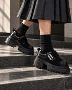 Chaussures à plateforme DIFFERENT portées avec chaussettes noires et jupe plissée, dans un escalier – DIFFERENT Paris