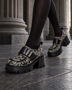 Chaussures à plateforme motif baroque DIFFERENT portées avec collants noirs, en marche devant des colonnes – DIFFERENT Paris