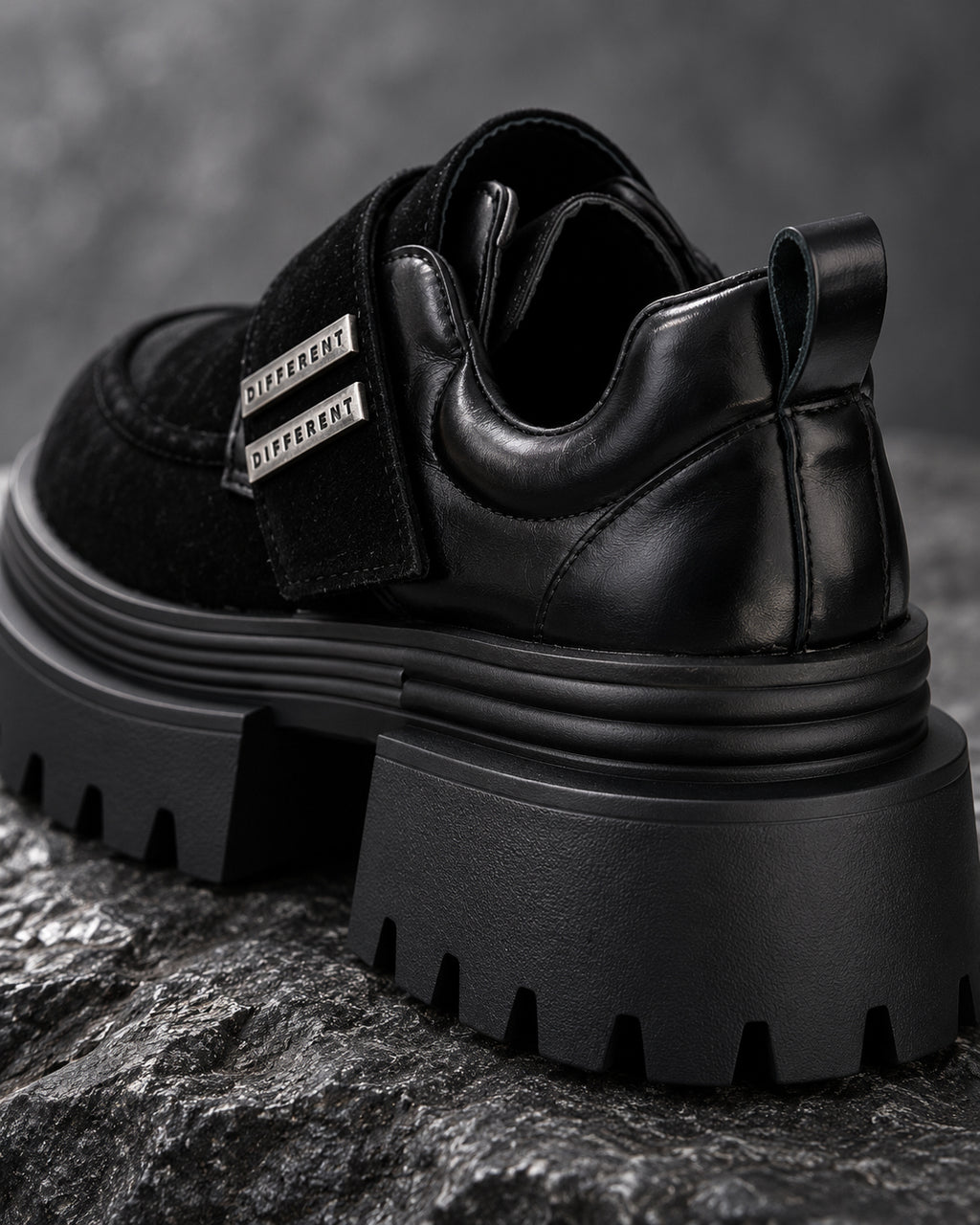 Gros plan arrière de la chaussure à plateforme noire DIFFERENT posée sur une roche, talon et semelle crantée – DIFFERENT Paris