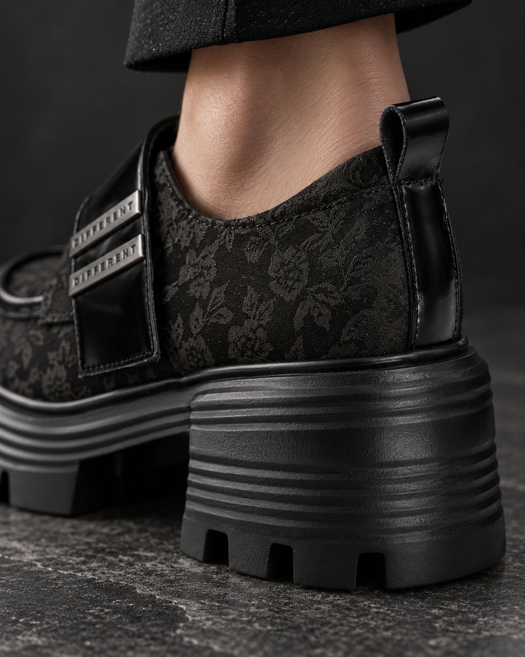 Gros plan arrière de la chaussure à plateforme noire DIFFERENT au motif floral ton sur ton, portée, talon et semelle crantée – DIFFERENT Paris