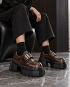 Chaussures à plateforme marron brillant DIFFERENT portées avec pantalon large noir et chaussettes noires, assise – DIFFERENT Paris