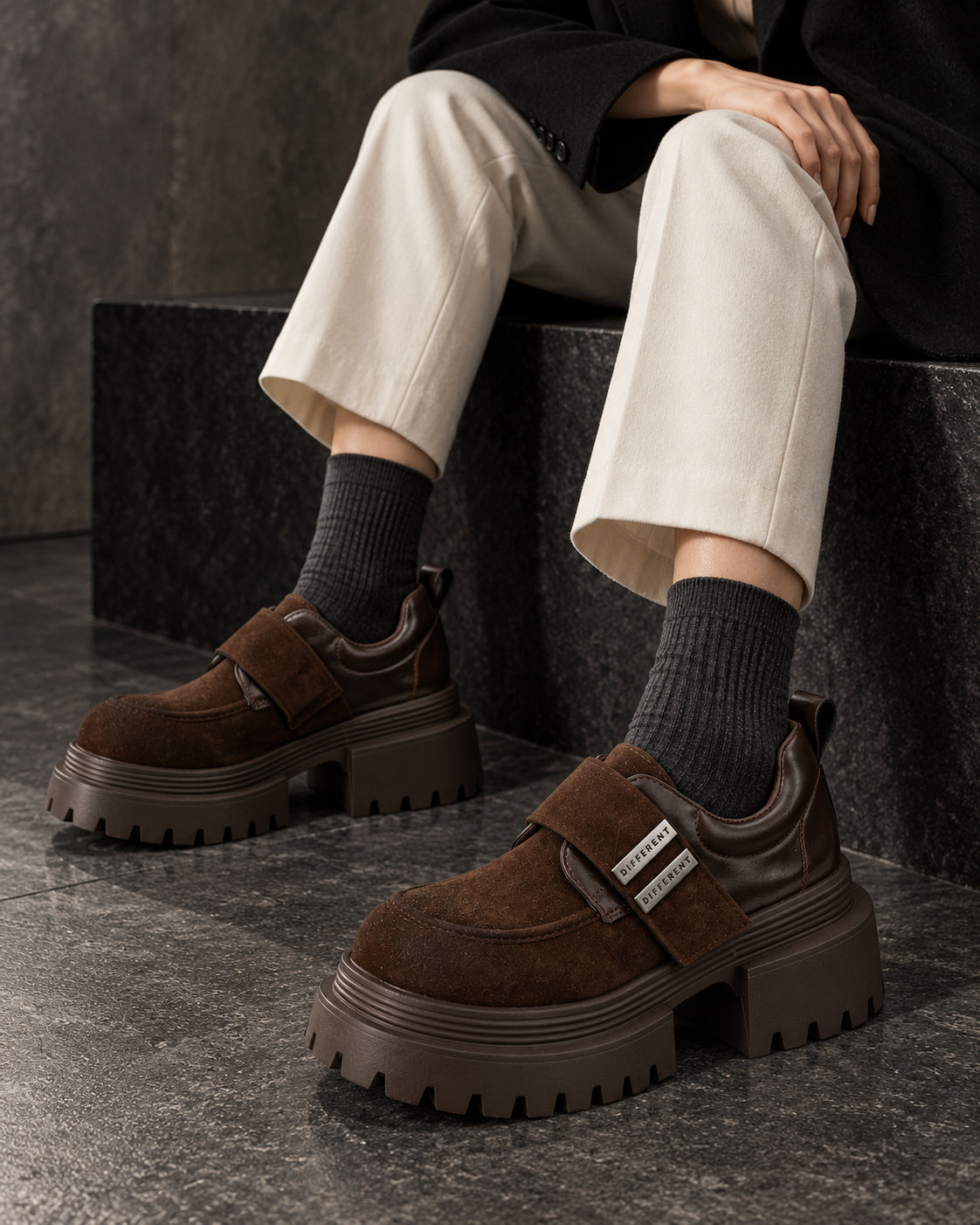 Chaussures à plateforme marron chocolat DIFFERENT portées avec pantalon crème et chaussettes grises, assise – DIFFERENT Paris