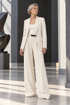 Veste longue ouverte et pantalon tailleur blanc à fines rayures, ceinture noire