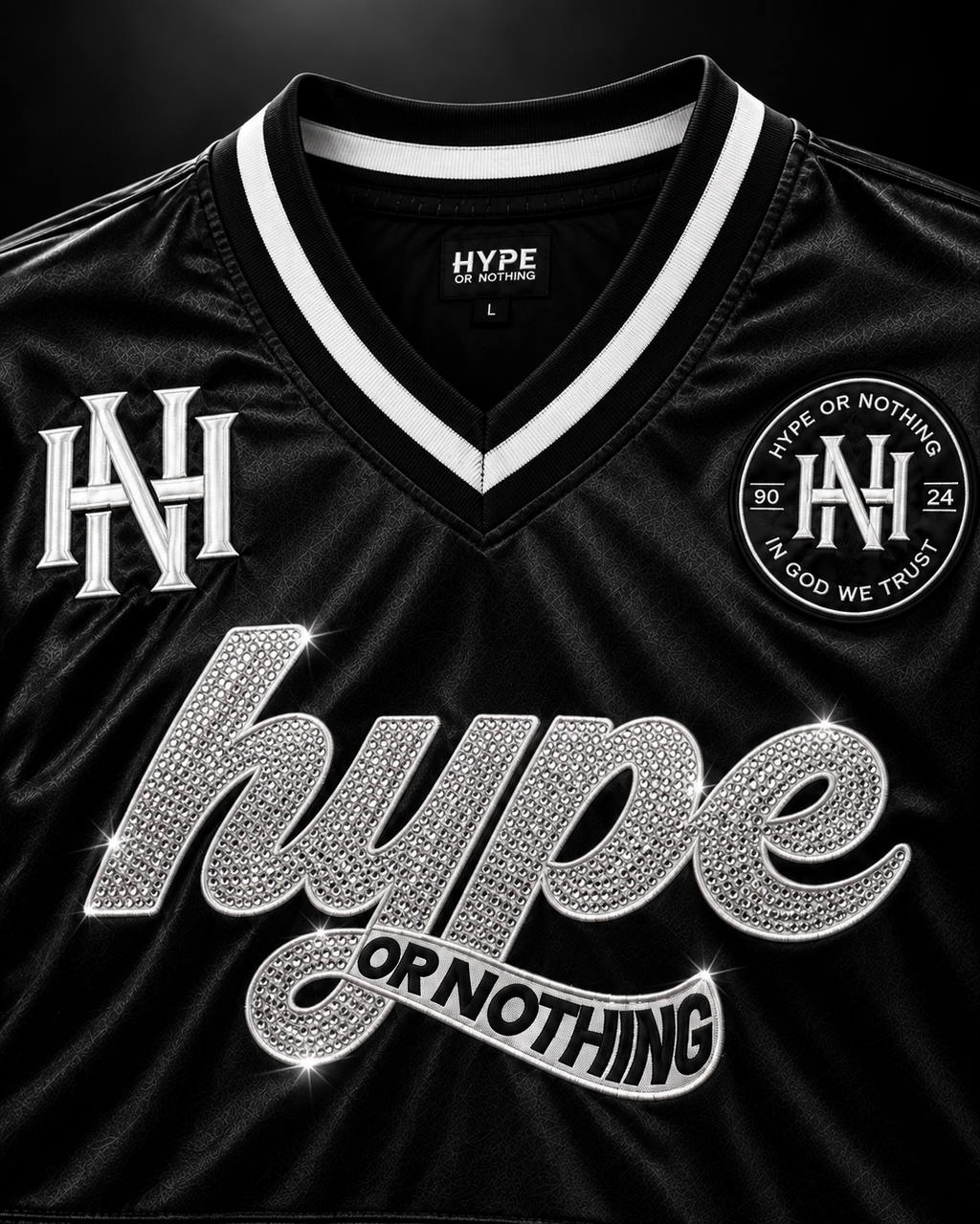 Détail du col V blanc, monogramme HN et script hype or nothing en strass – DIFFERENT Paris